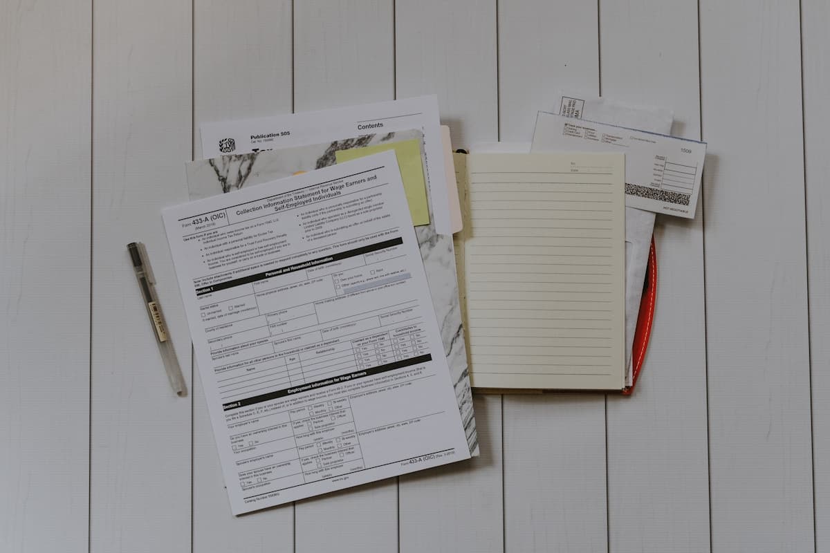 Official forms with checkboxes and a notebook laid out on a white table