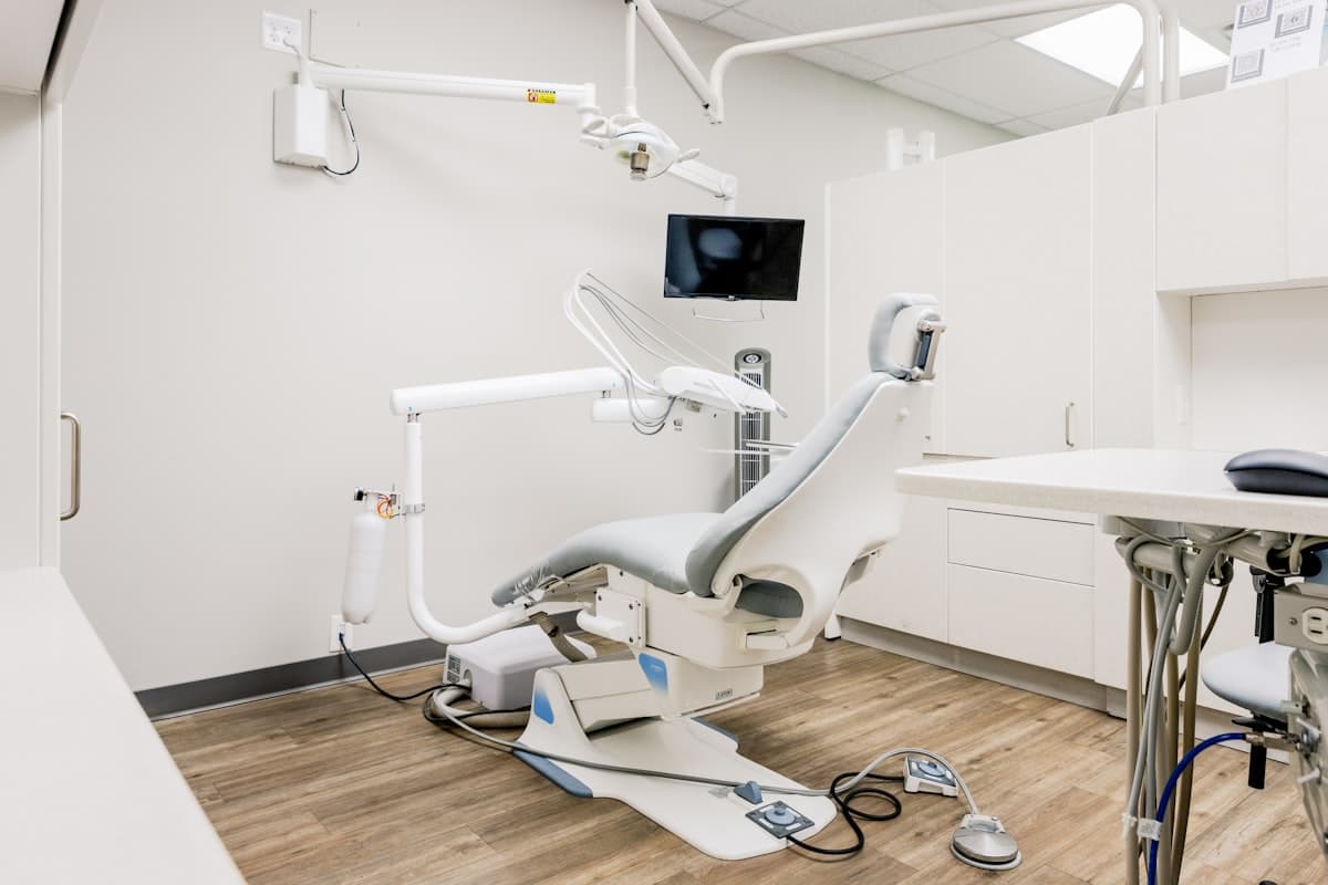 An empty dental operatory with a dark wall-mounted monitor and cabling across the floor
