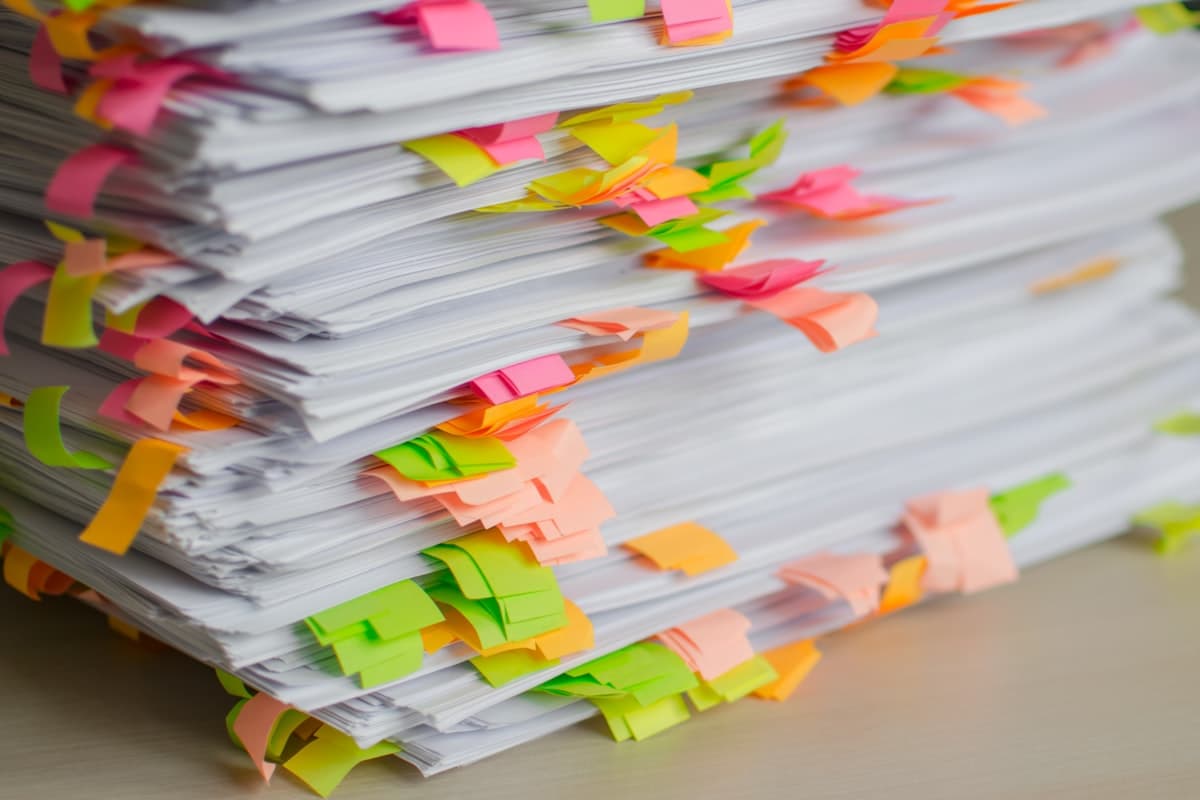 A tall stack of paper marked with dozens of colored sticky tabs